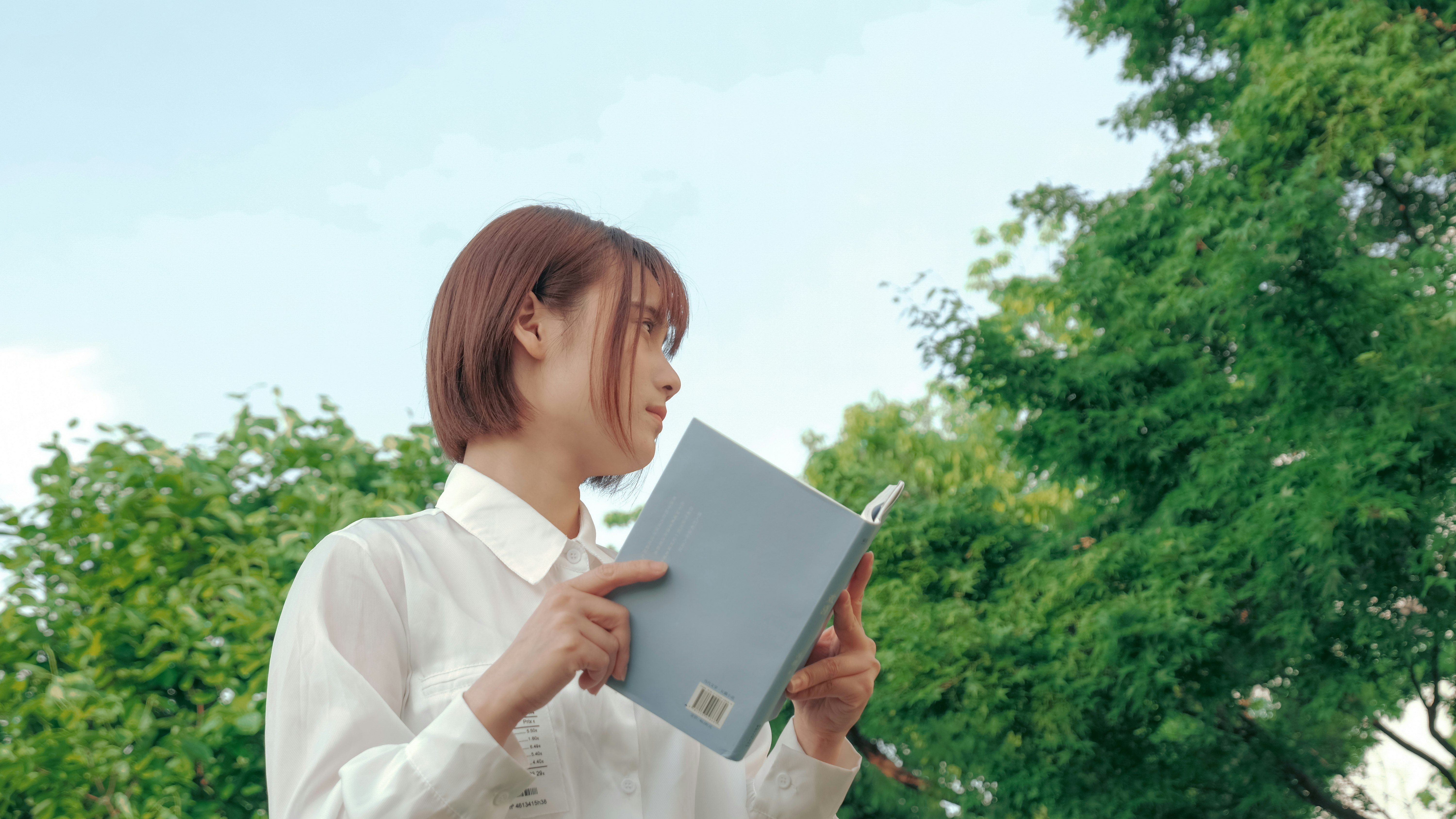 woman in white dress shirt holding black tablet computer